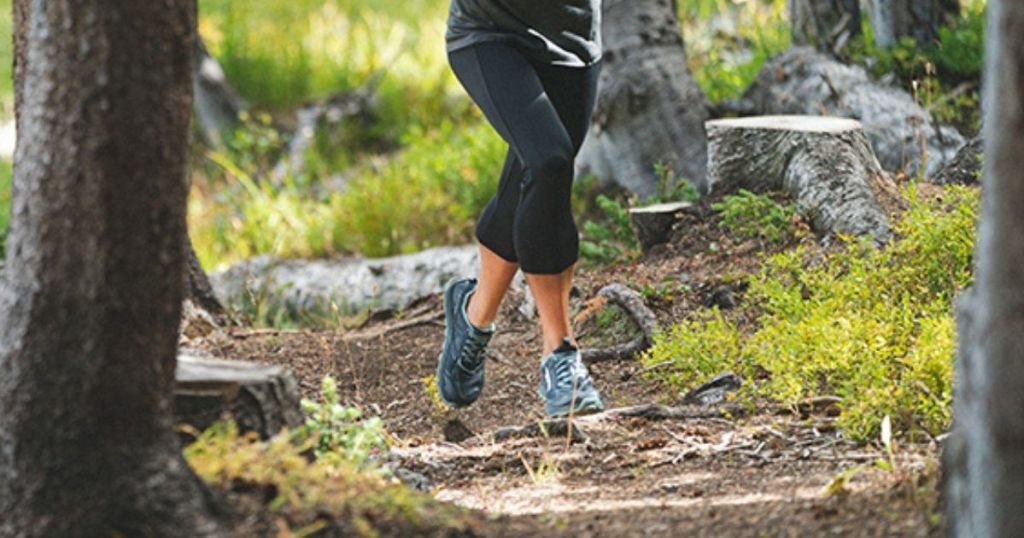 woman wearing altra lone peak trail running shoes running in the woods