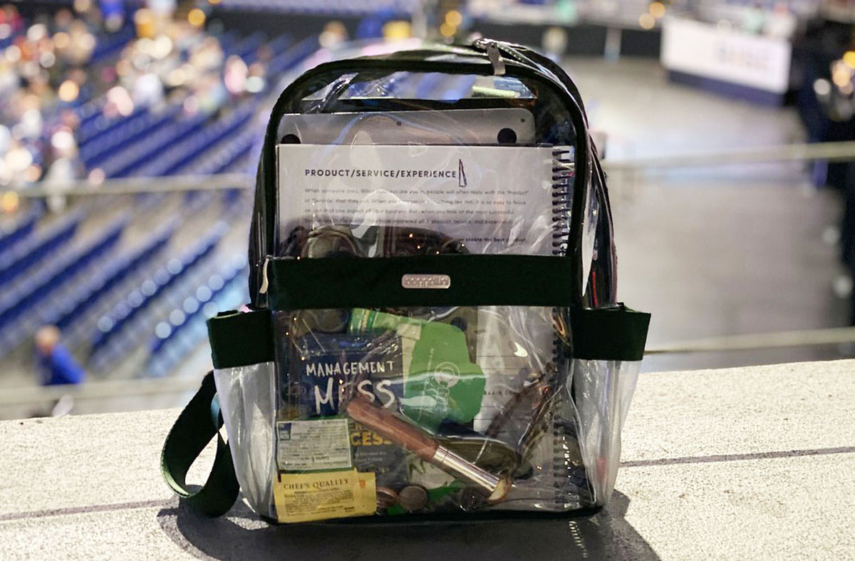 a clear backpack full of items sitting on the edge of a ledge overlooking a stadium