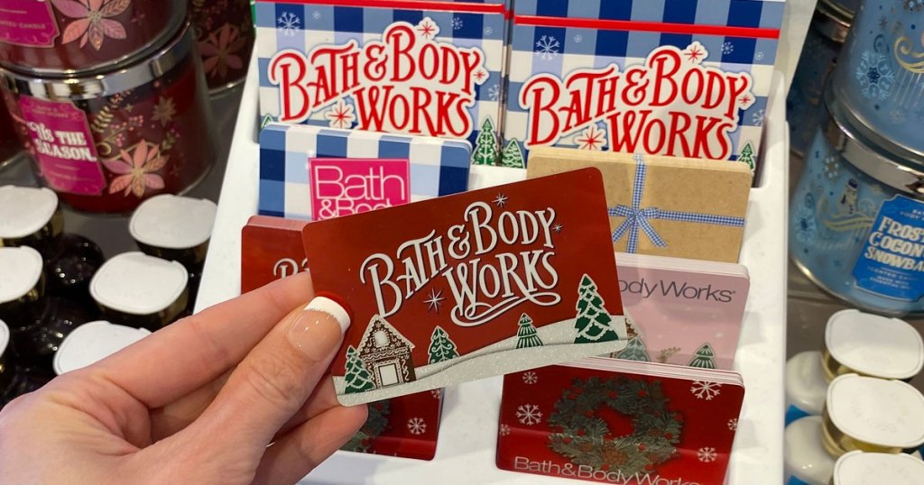 person holding up a red christmas themed bath & body works gift card