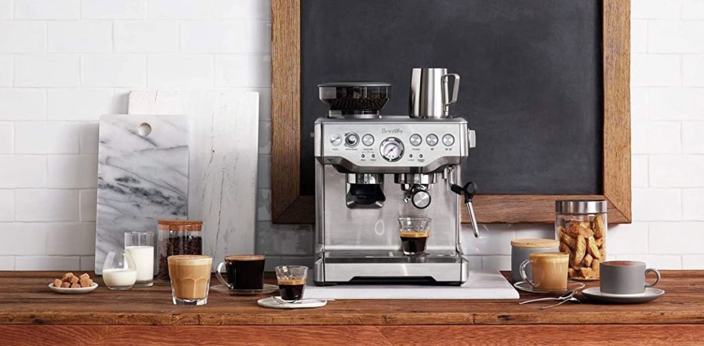 Breville Barista Express espresso maker on a table with coffee next to it