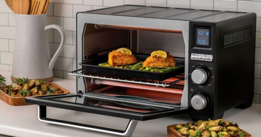 Calphalon Precision Air Fry Convection Oven with door open and two pieces of chicken inside of it with vegetables in plates on the side