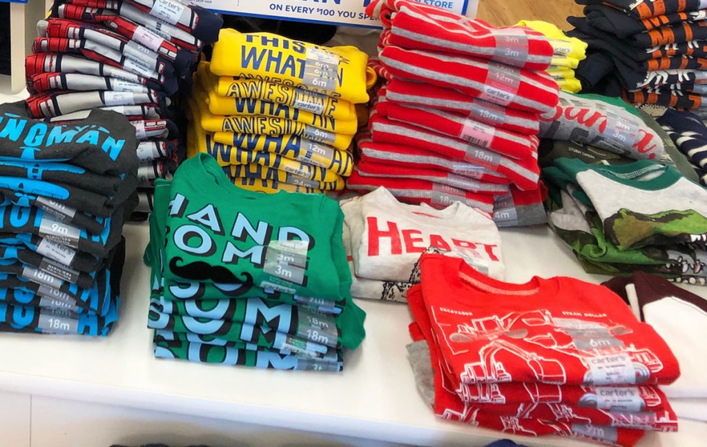 white display table full of folded stacks of boys graphic tees
