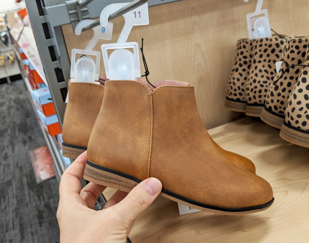 person holding a pair of brown cat & jack toddler booties at target