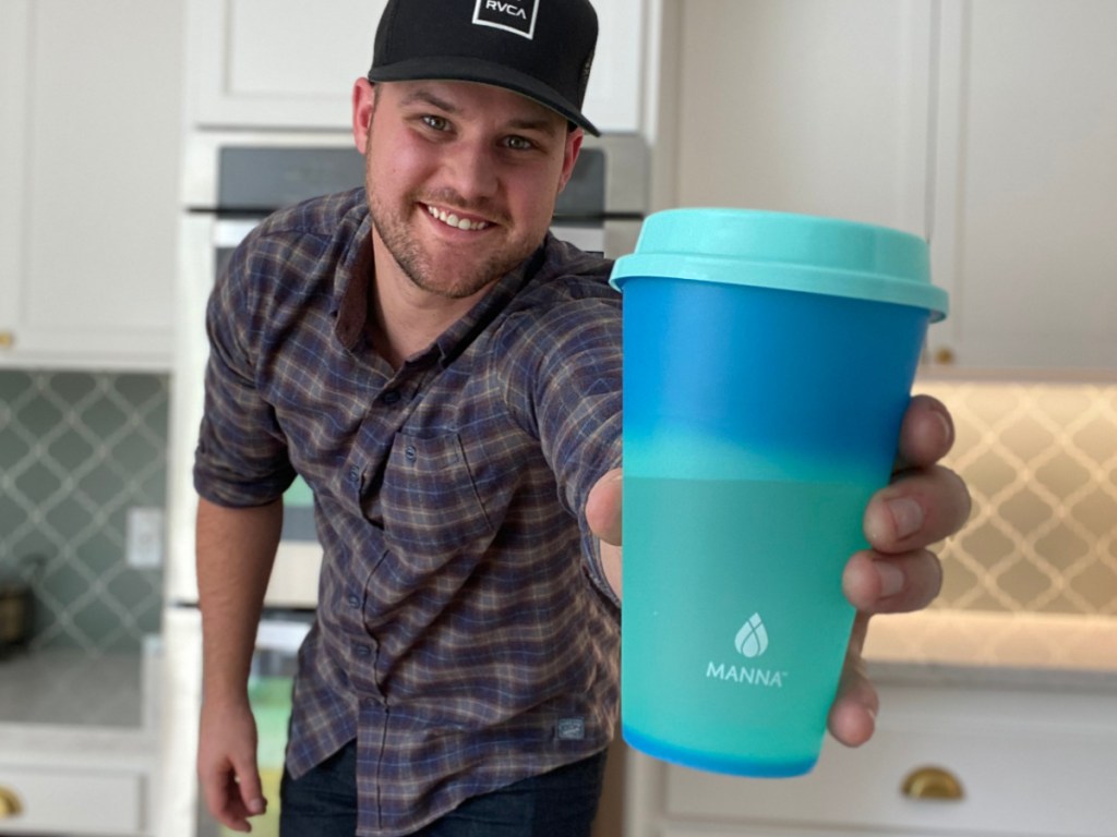 man holding a teal colored costco color changing tumbler with a lid and straw