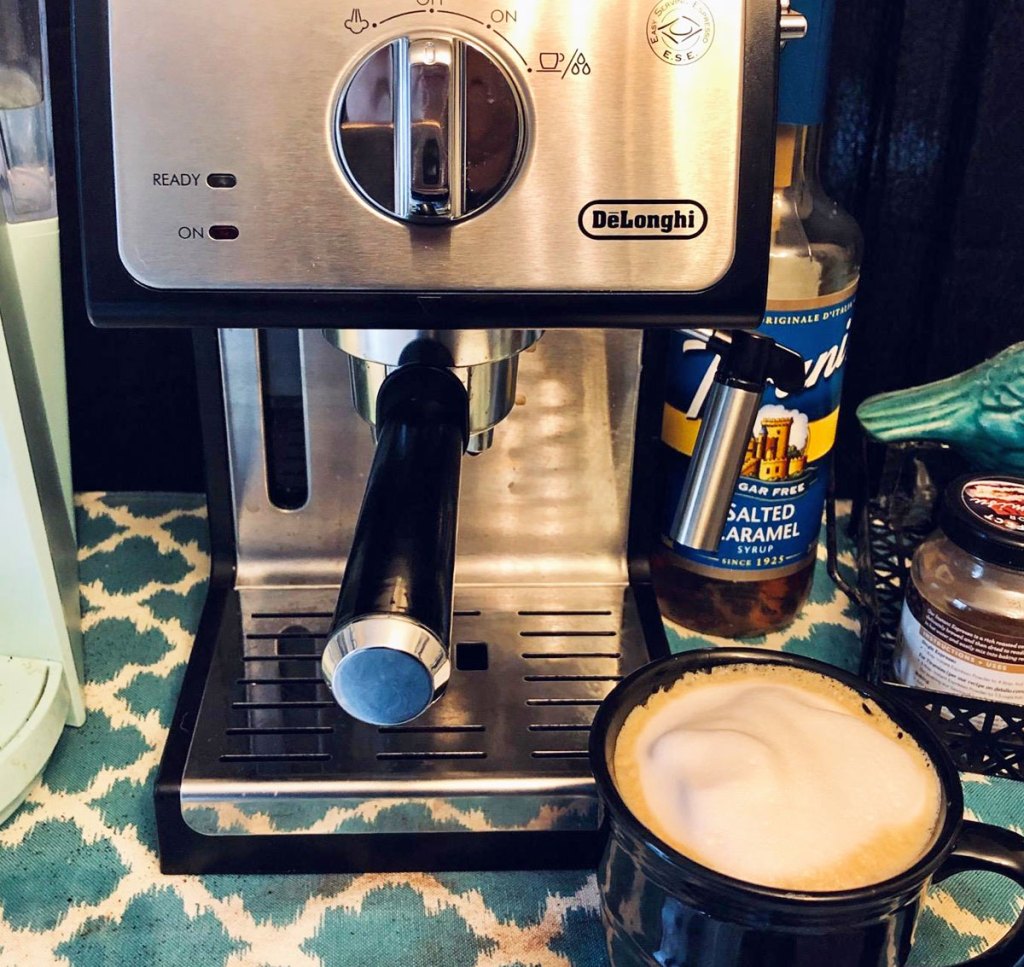 stainless steel expresso machine on counter with cup of cappuccino in front of it
