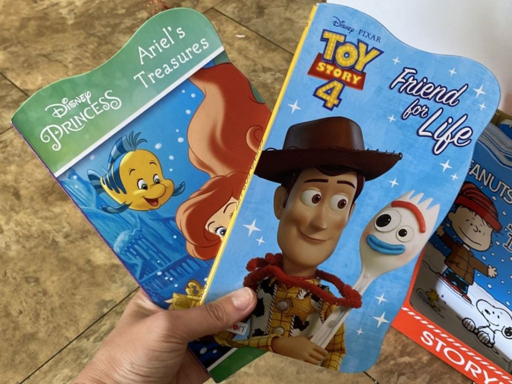 Woman holding two character kids books 