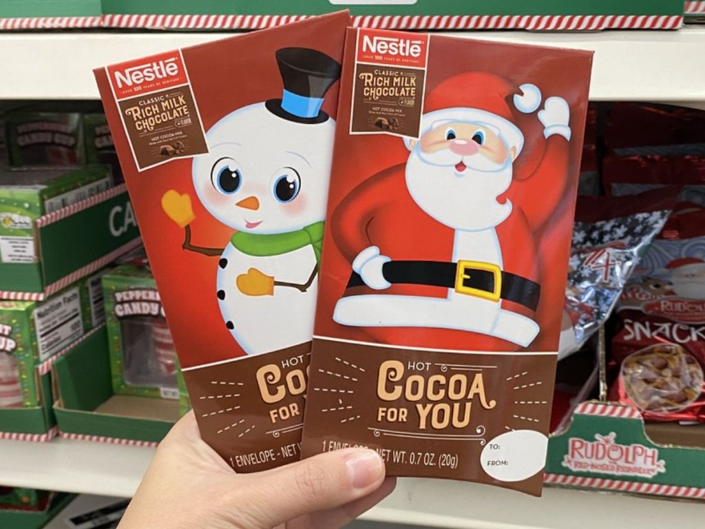 WOman holding two packets of Nestle Holiday Theme Cocoa Mix Packs