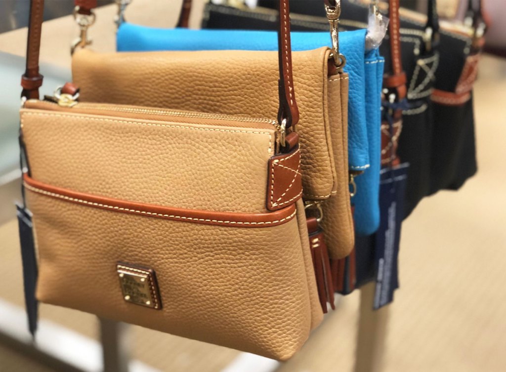 leather dooney & bourke crossbody bags hanging from a store display