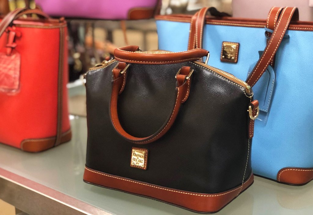 black leather dooney & bourke satchel on table in front of other colorful leather bags