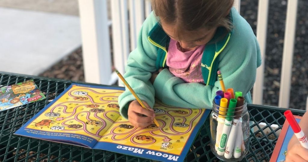 Little Girl writing in Highlights Puzzle Buzz Book