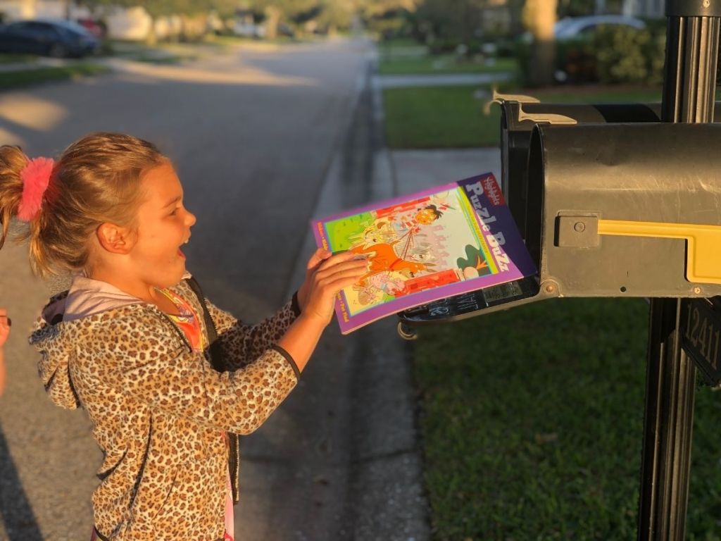 girl taking a magazine out of a mailbox