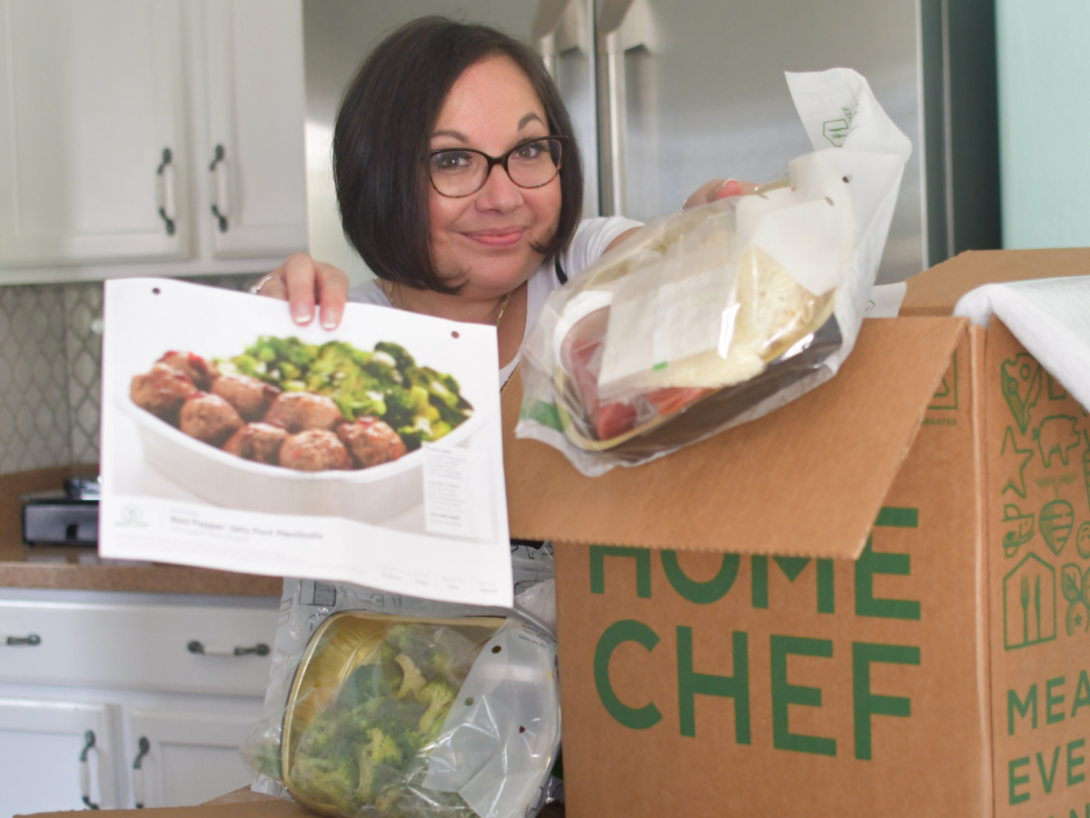 women holding a recipe and ingredient next to home chef box