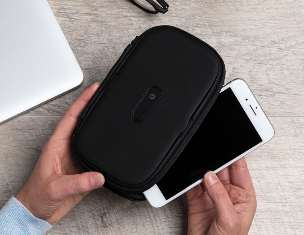 person placing a white iphone into a black sanitizing case
