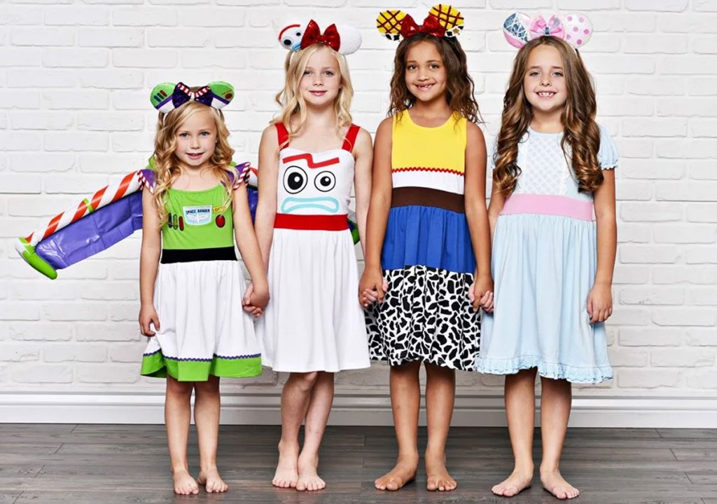 four girls standing and holding hands wearing toy story themed dresses