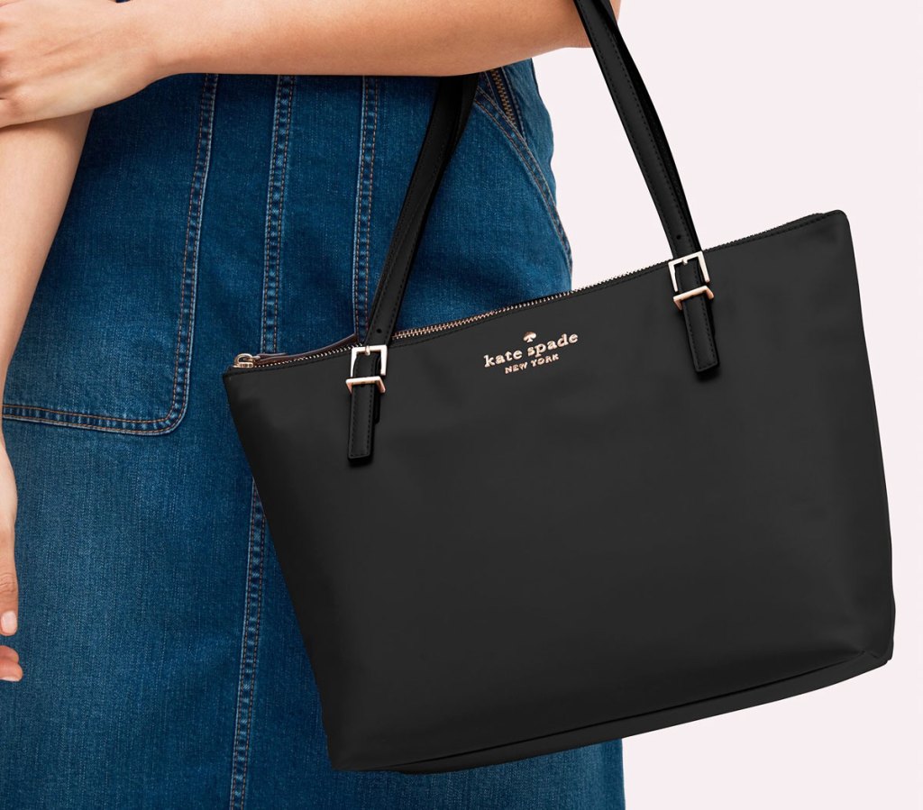 woman in a denim shirt with a small black kate spade tote on her arm
