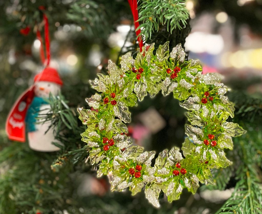 glittery wreath shaped ornament hanging on a christmas tree