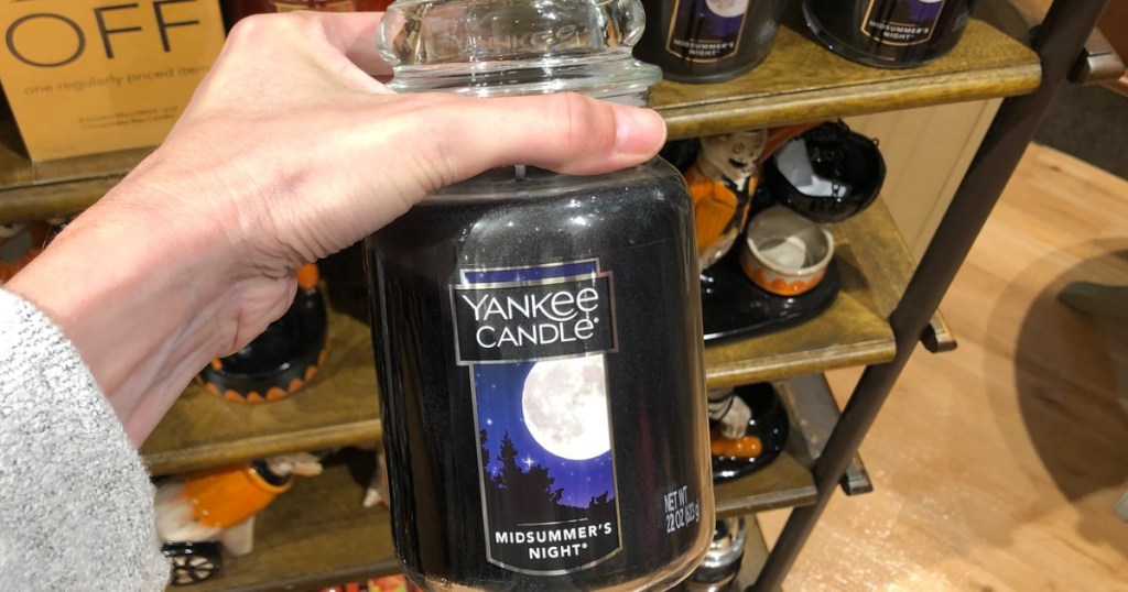 hand holding a large yankee candle midsummer nights dream