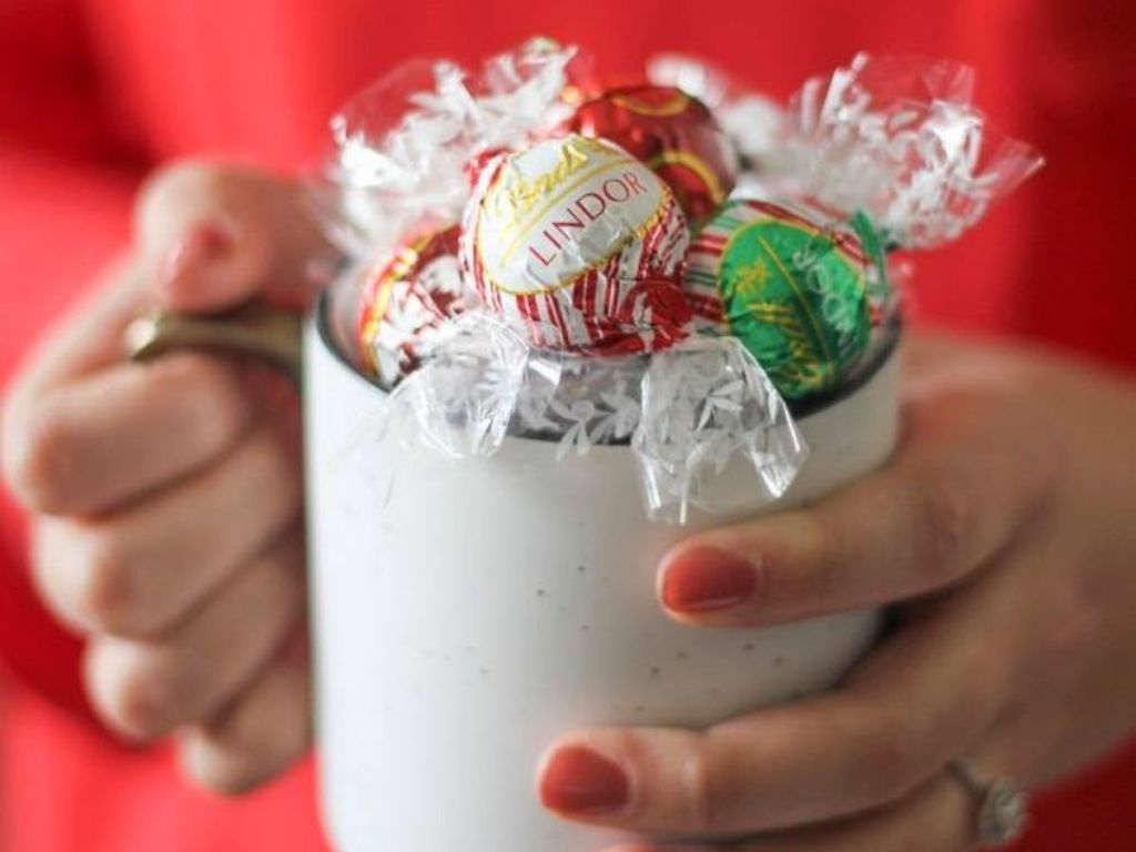 woman holding white mug with Lindt Lindor Holiday Truffles