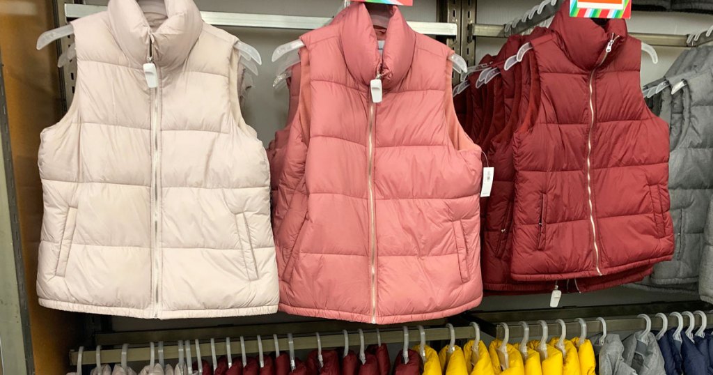 white, pink, and red women's puffer vests hanging on store display at old navy