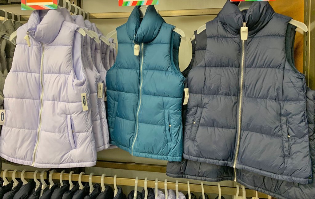 women's puffer vests in shades of blue on hangers on store display at old navy