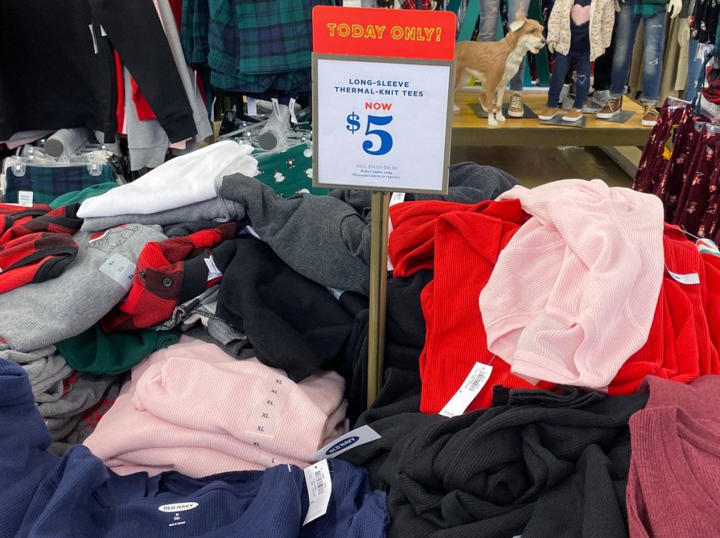 pile of women's long-sleeve thermal tops with a $5 sale sign