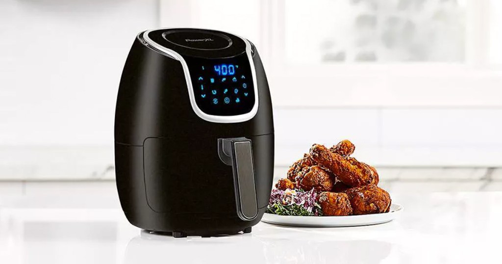 black air fryer on kitchen counter next to plate of fried chicken