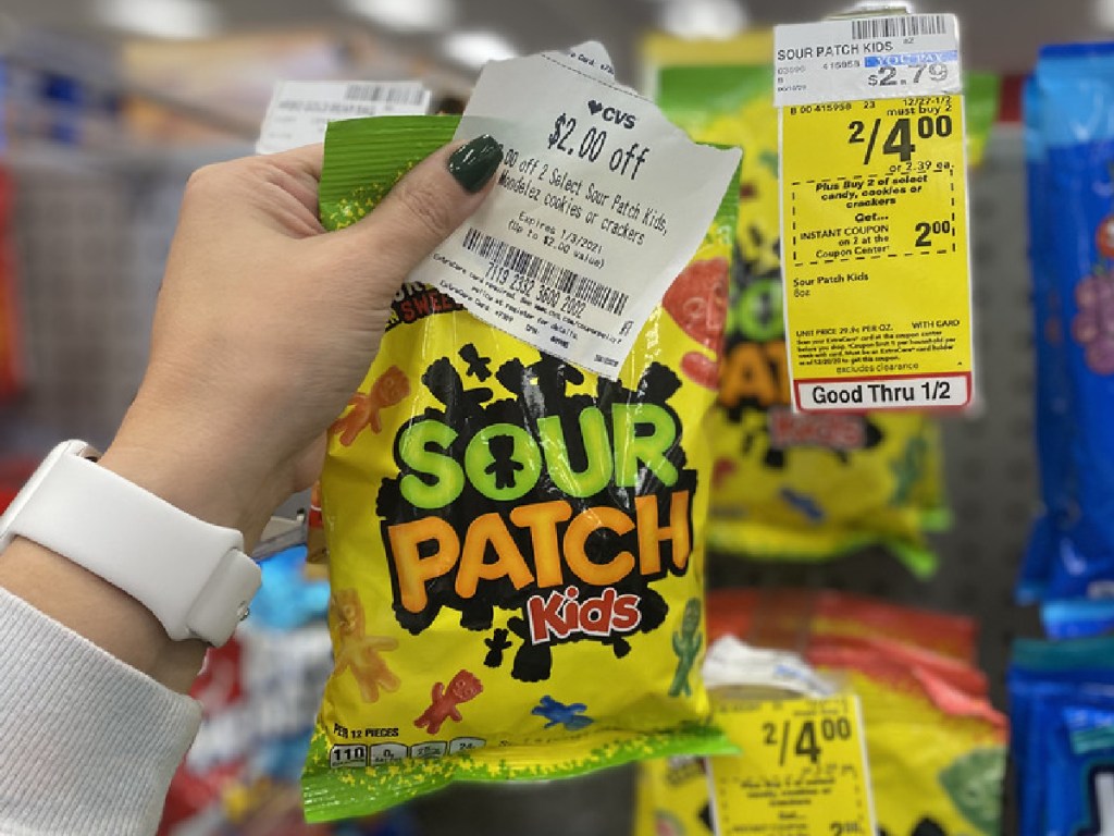 woman's holding bag of candy and coupon in store