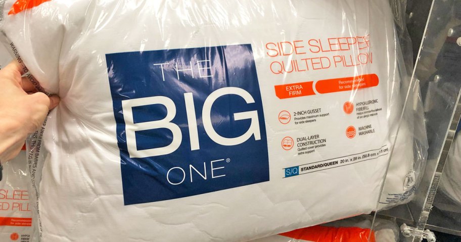 woman holding up the big one quilted side sleeper pillow in plastic packaging