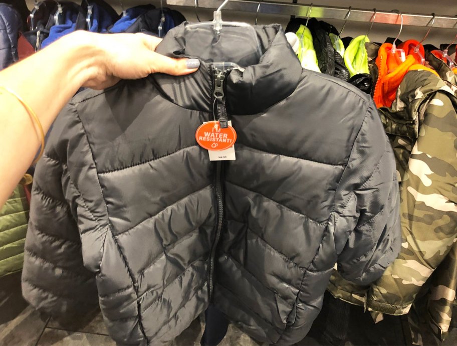 woman holding up a toddler boy's black puffer jacket