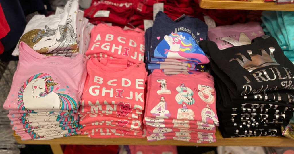 girls graphic tees folded on display table in store
