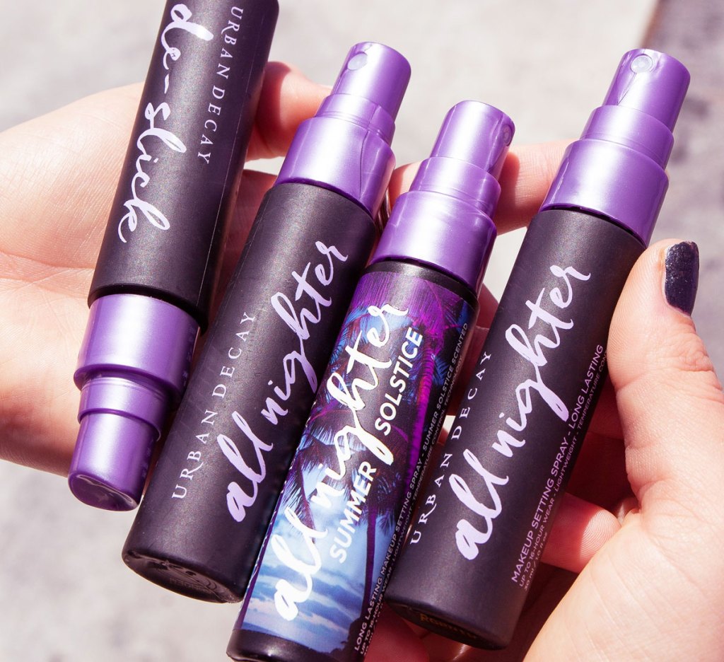 hands holding four travel size bottles of urban decay makeup setting sprays