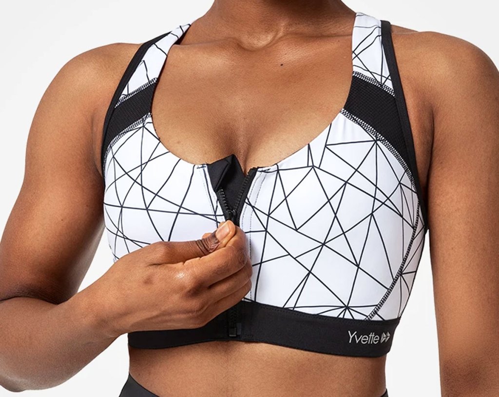 woman zipping up the front of a black and white geometric print sports bra