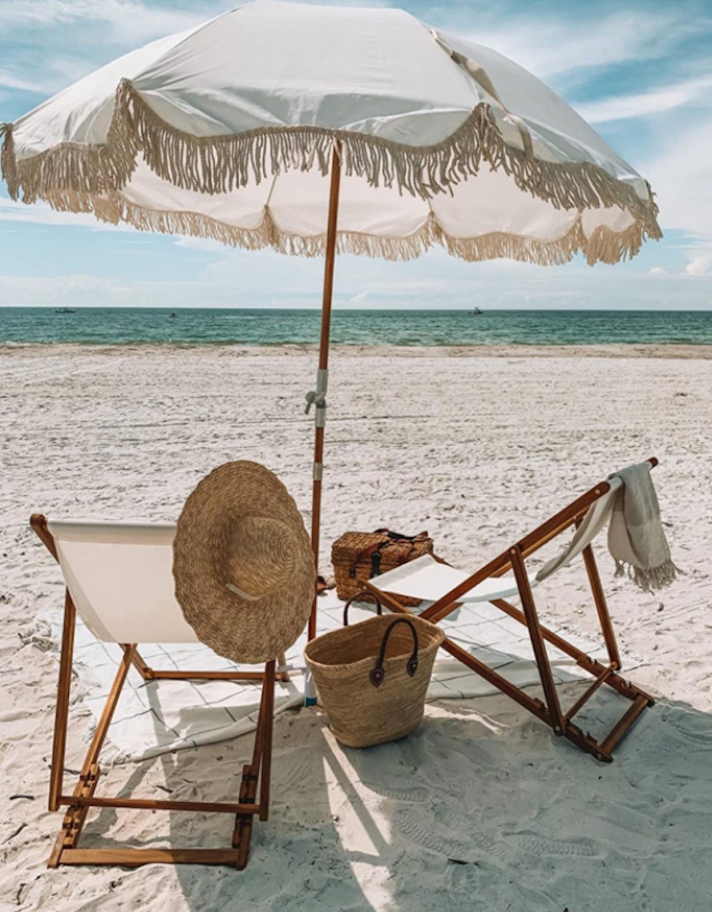 wood and white sling chairs on beach with tassel beach umbrella