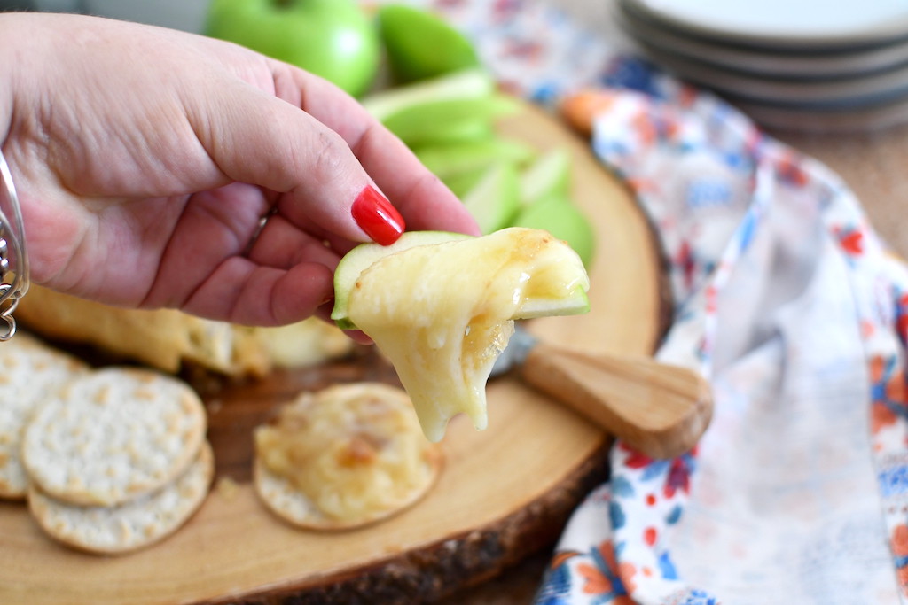 holding sliced apple with brie cheese