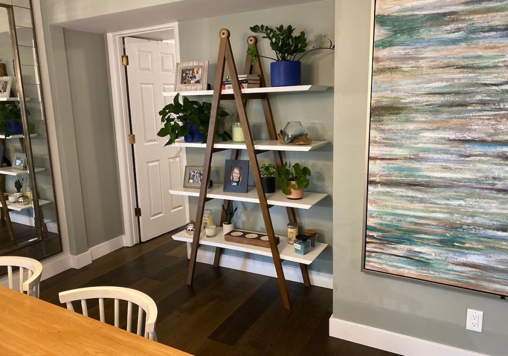a frame article shelf sitting on wood floor in dining room with various decor
