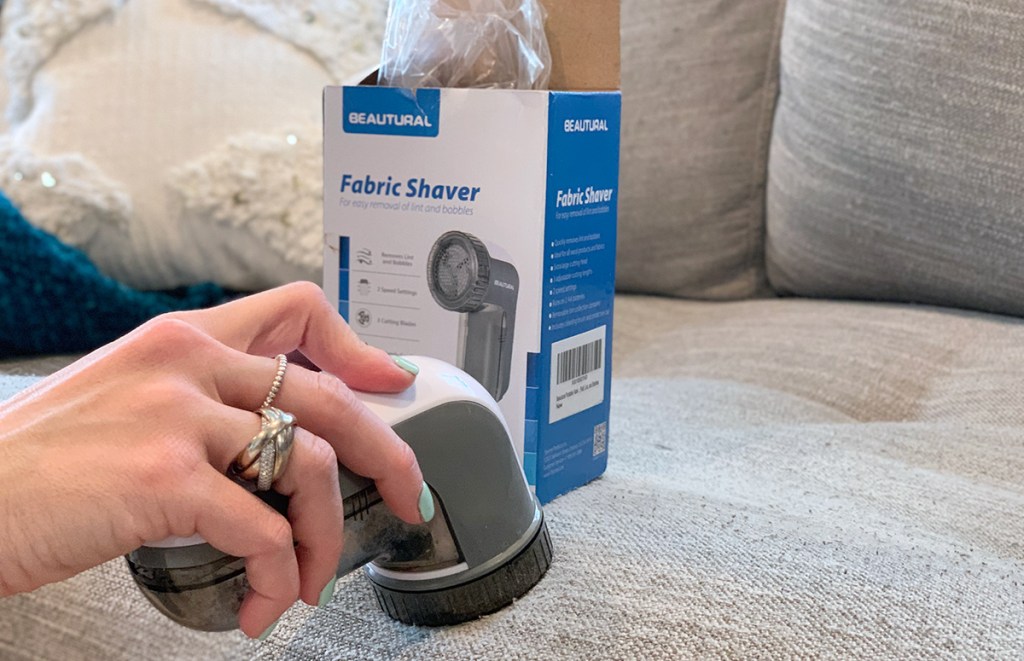 hand holding a fabric shaver on article furniture couch