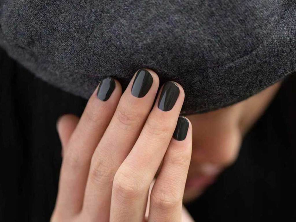 black nail polish on hand touching hat