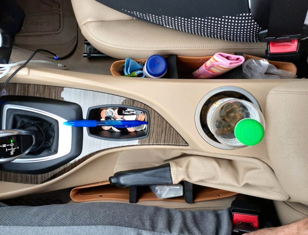 brown car organizers between seats with small accessories inside
