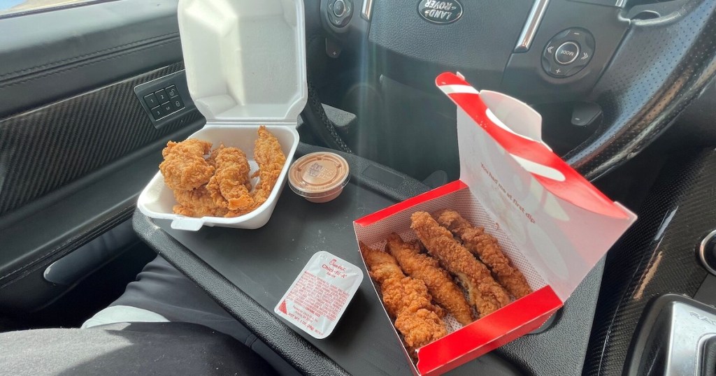 steering wheel inside car with tray clipped on it and takeout food on top