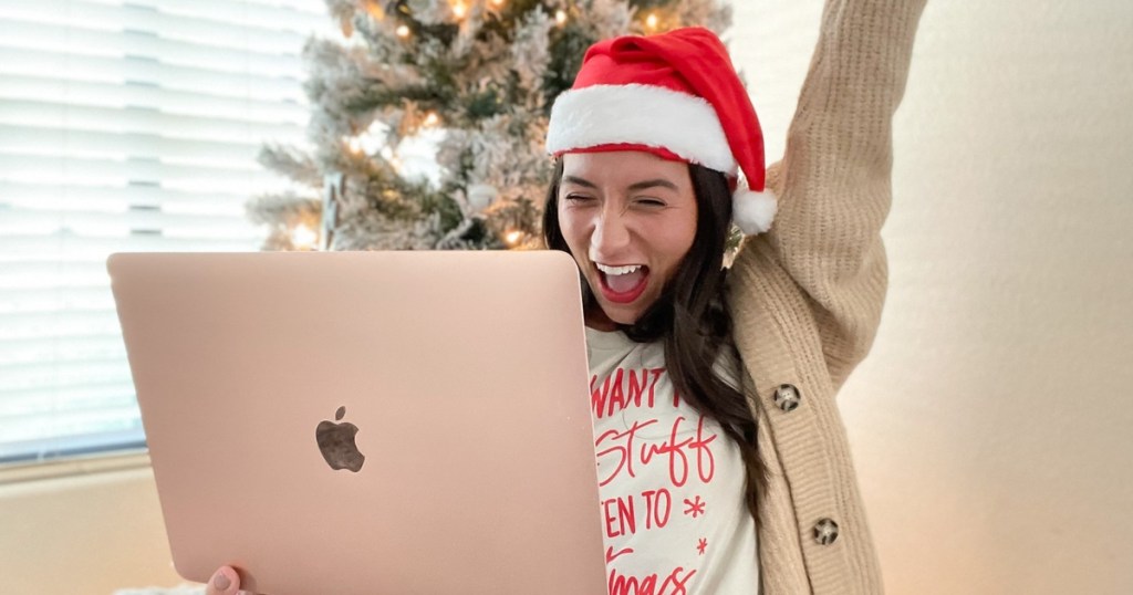 woman with laptop and Santa hat cheering when is black friday