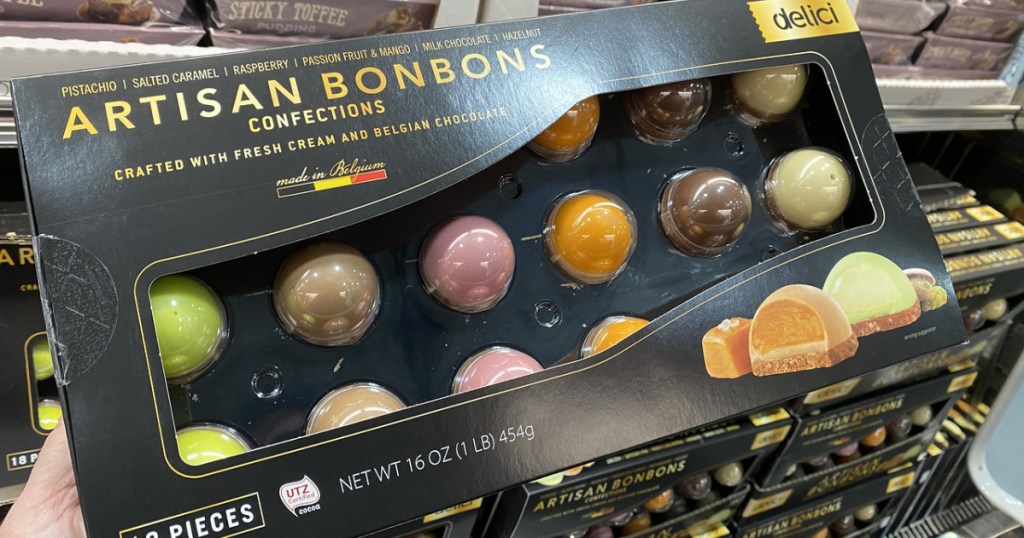hand holding box of chocolate bonbons by store display