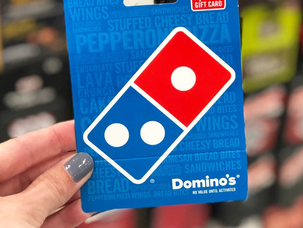 person with grey nails holding up a blue and red dominoes pizza gift card