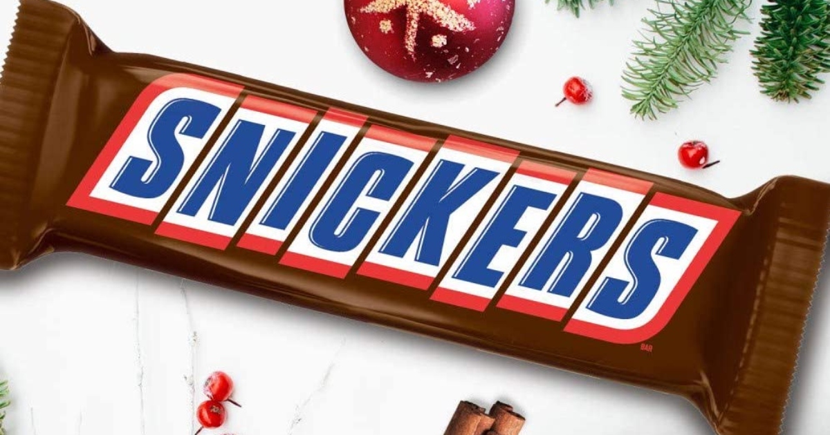 giant snickers bar with ornaments and Christmas tree clippings nearby