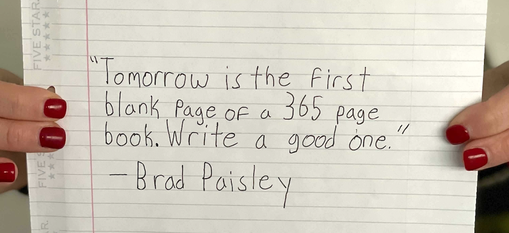 holding New Year quote written on piece of paper 