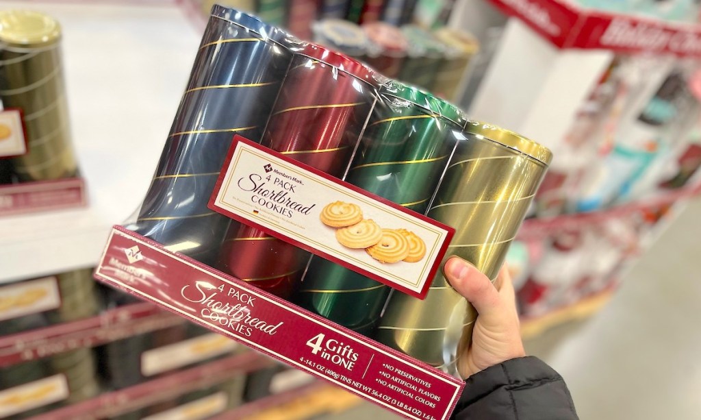 hand holding four different colored tins with shortbread cookies 
