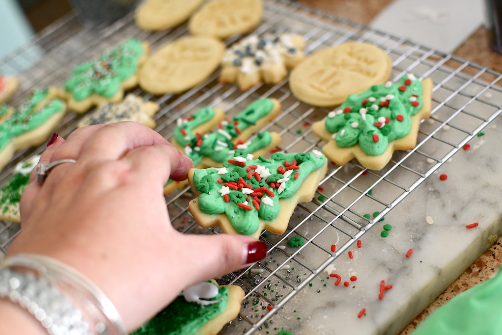 woman picking up frosted sugar cookie 