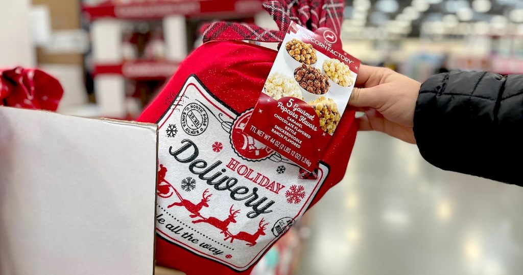 hand pulling christmas delivery bag with popcorn inside off store shelf - sams club gifts