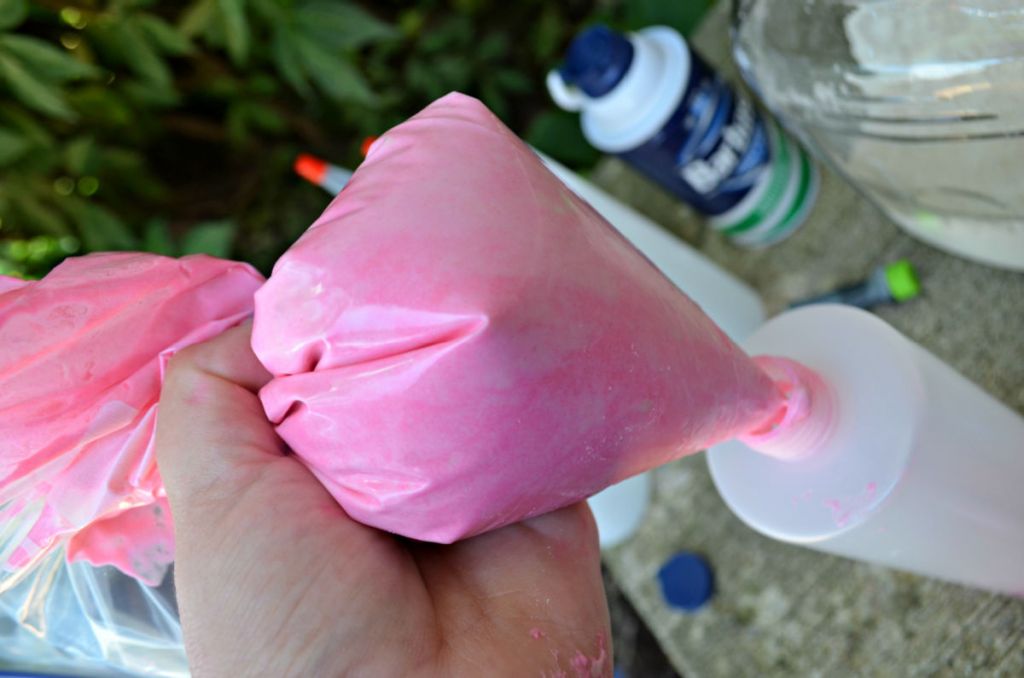 using plastic bag to squeeze pink paint into bottle