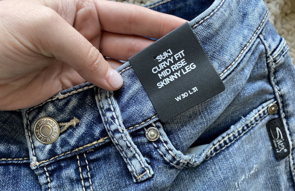hand holding pair of jeans with tags on them