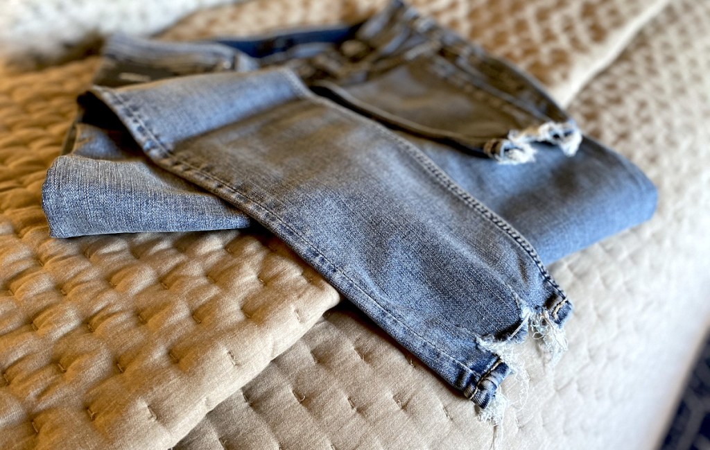 silver jeans sitting on quilt 